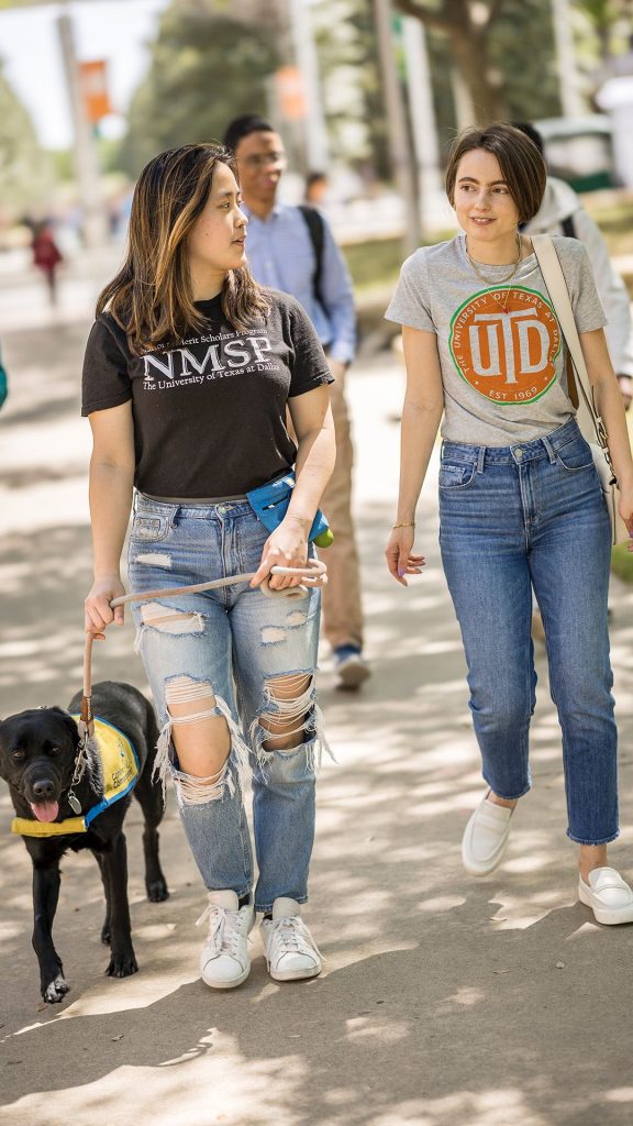 two students walking a black dog