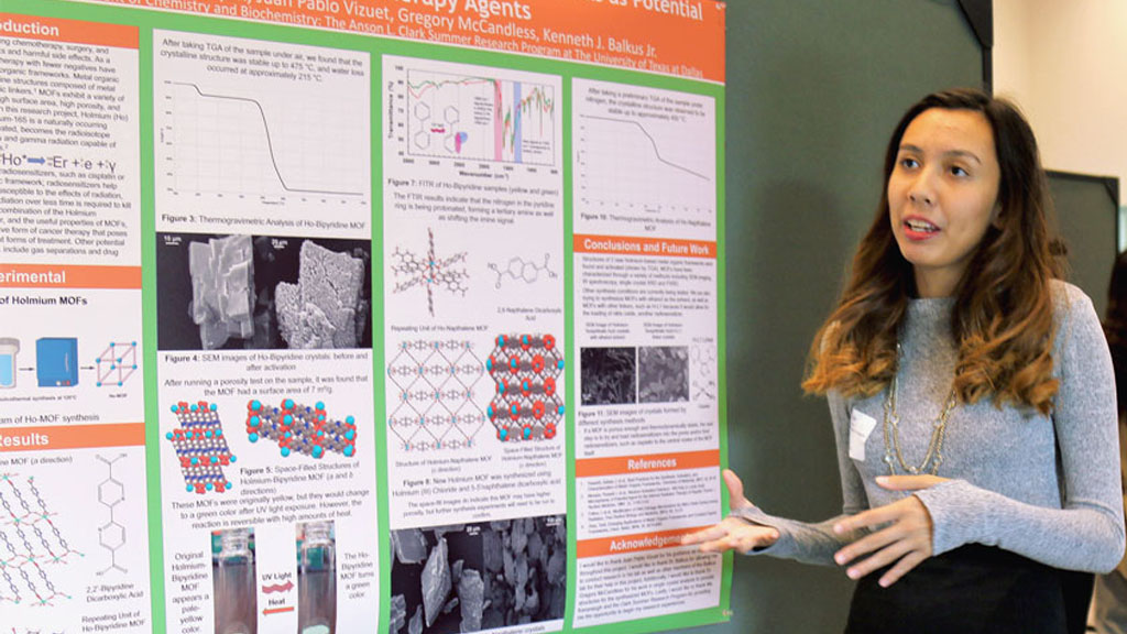 A Clark Scholar discusses her research in front of a poster.